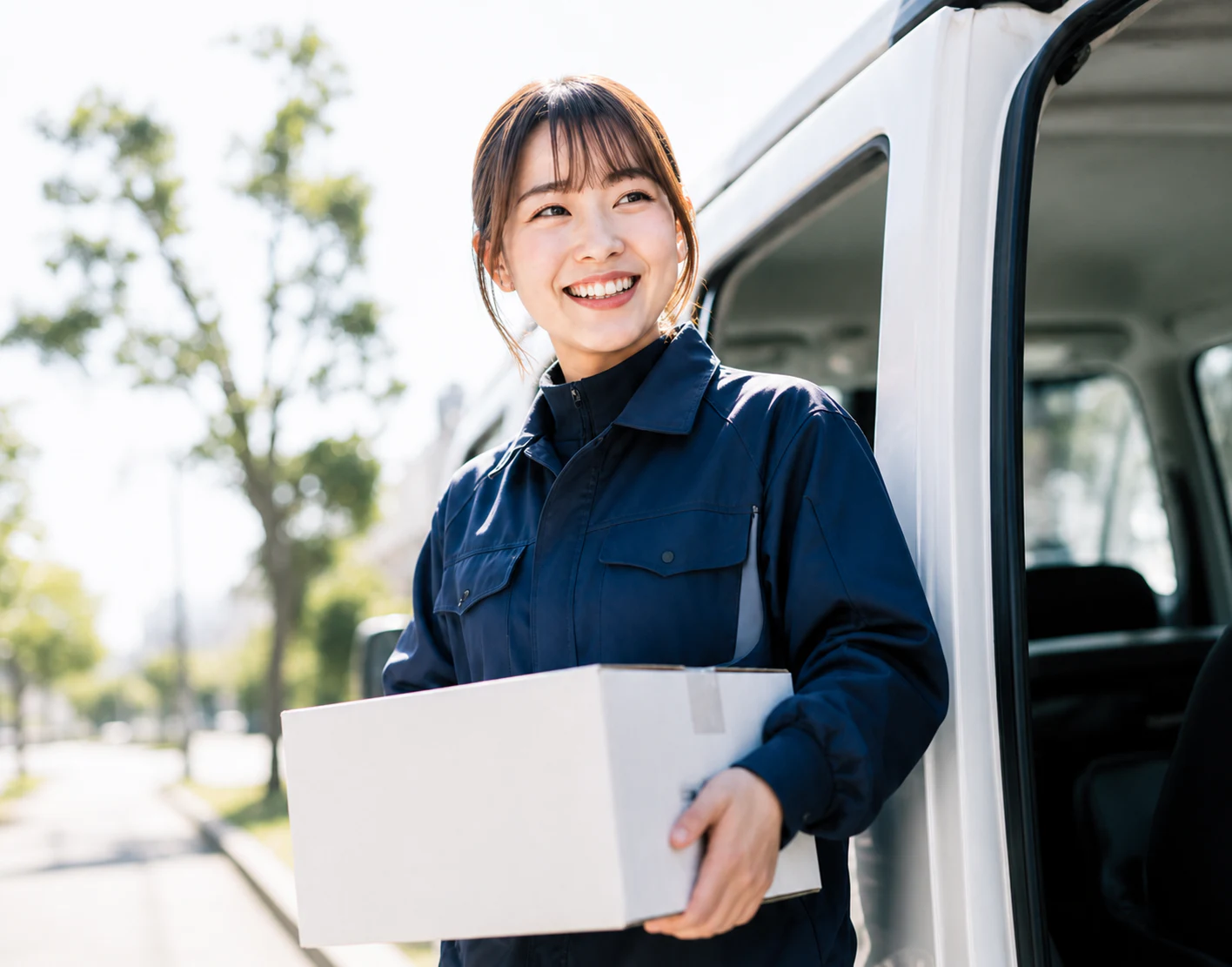 配送スタッフが荷物を持って笑顔で立っている様子